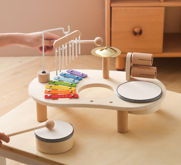 Children's wooden musical toy set with various instruments on a light wooden surface.