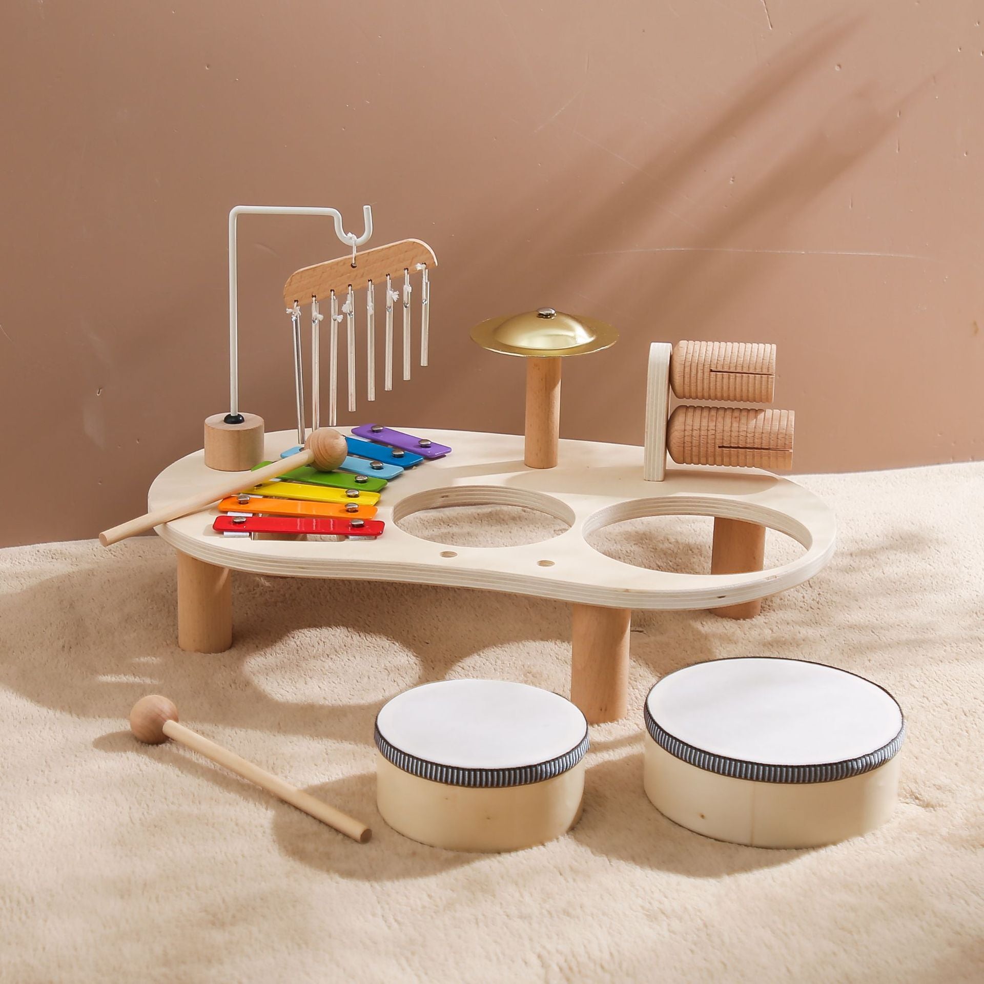 Set of wooden musical instruments on a sandy surface with a beige background