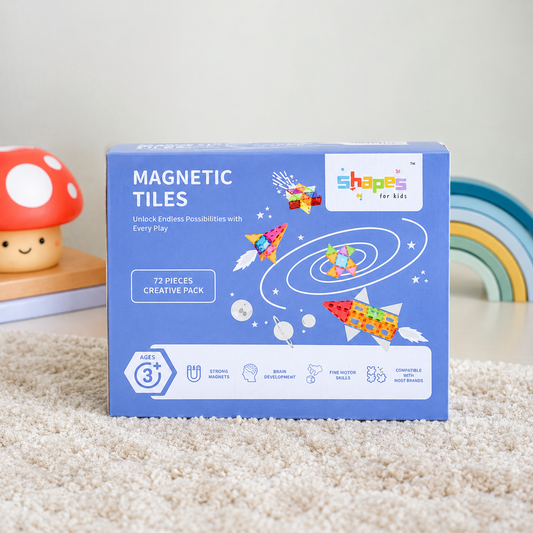A blue box of Shapes for Kids Magnetic Tiles, 72-piece creative pack, displayed on a beige carpet with a mushroom toy and rainbow in the background.