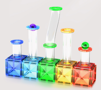 Five colorful transparent magnetic building blocks with attached clear tubes and colored circular tops, arranged in a row on a light gray background.